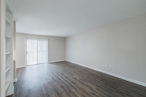 A room with wooden floors and a window with blinds.