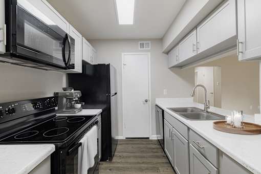 A kitchen with black appliances and white countertops.