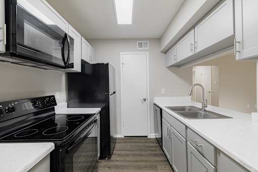 A kitchen with black appliances and white countertops.