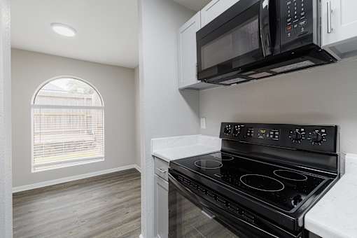 A black microwave oven is mounted above a black stove in a kitchen.