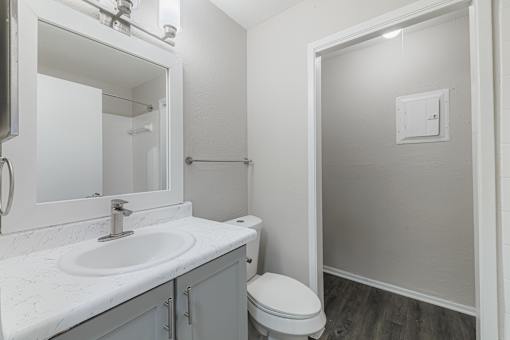 A white bathroom with a toilet, sink, and mirror.