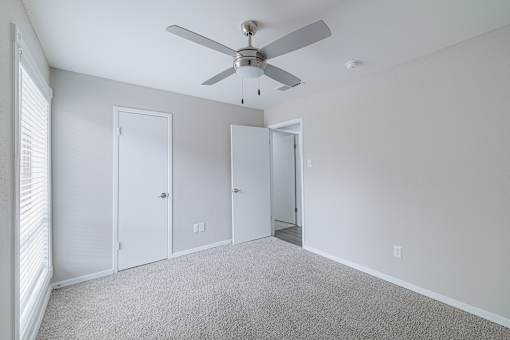 A room with a ceiling fan and three doors.