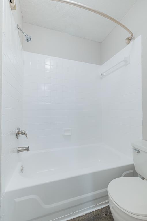 A white toilet sits next to a white bathtub in a bathroom.