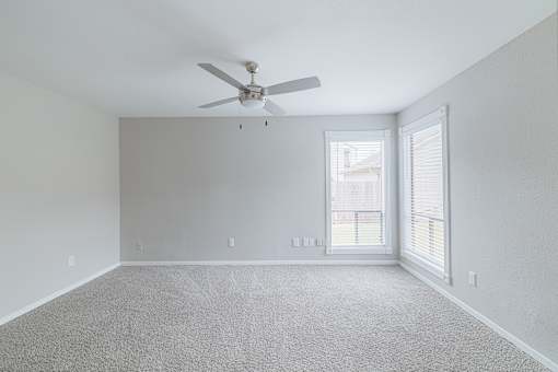 A room with a ceiling fan and carpeted floor.