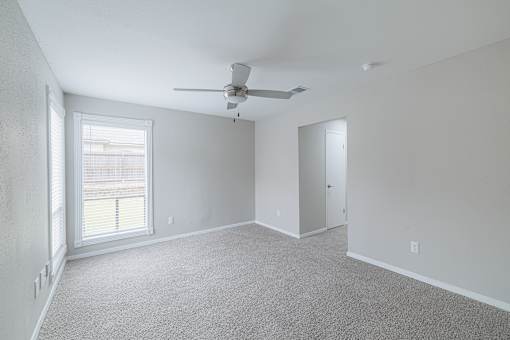 A room with a ceiling fan and a window with blinds.