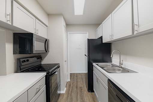 A kitchen with black appliances and white cabinets.