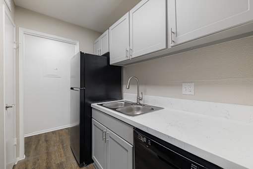 A kitchen with a black refrigerator and a white counter.