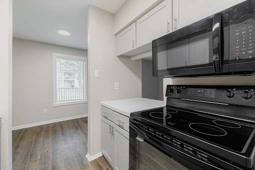 A black microwave is mounted above a black stove in a kitchen.