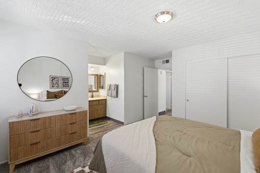 A bedroom with a bed, dresser, and mirror.