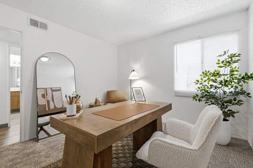 A room with a wooden table, a white chair, and a potted plant.