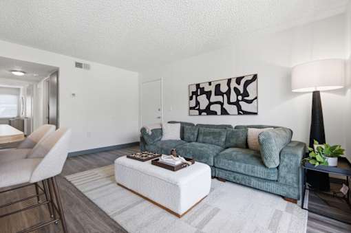 A living room with a green couch and a painting on the wall.