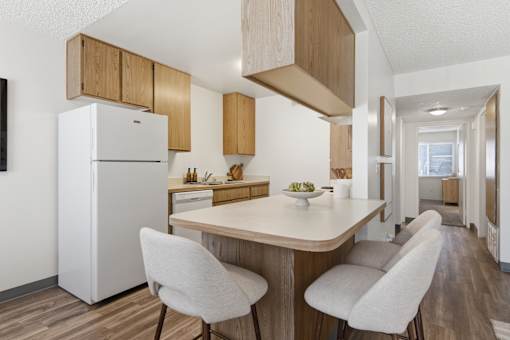 A kitchen with a white refrigerator and a table with two chairs.