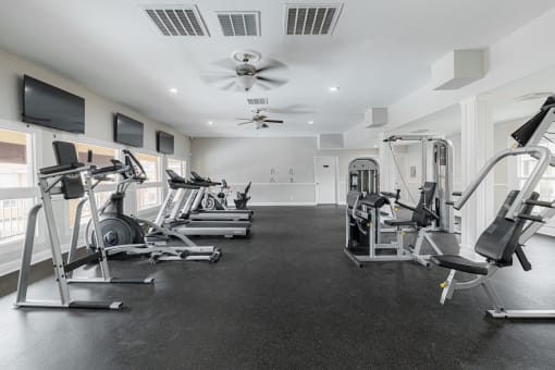 a gym with exercise equipment and a ceiling fan