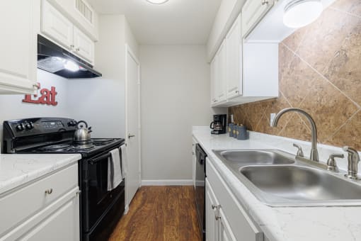 a kitchen with white cabinets and black appliances and a sink