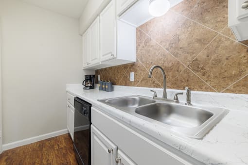 a kitchen with white cabinets and a stainless steel sink