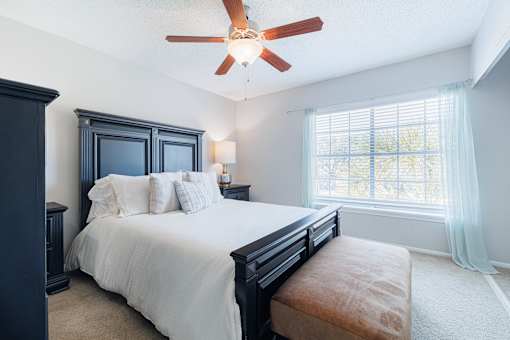 A bedroom with a bed, nightstand, and window.