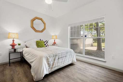 A bedroom with a bed, two lamps, and a mirror on the wall.