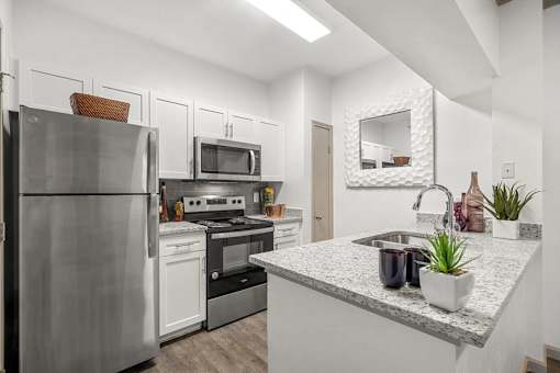 A modern kitchen with a stainless steel refrigerator, microwave, oven, and sink.