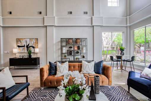 A living room with a brown sofa and a coffee table with a vase of flowers on it.