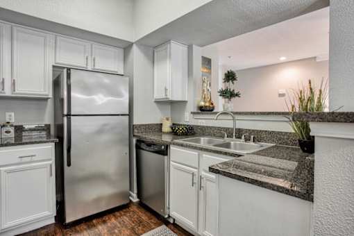 A kitchen with white cabinets and a stainless steel refrigerator.