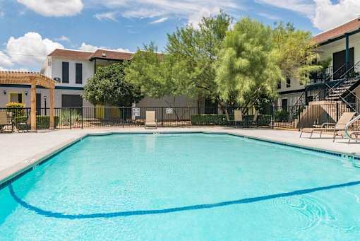 A swimming pool surrounded by a fence and trees.