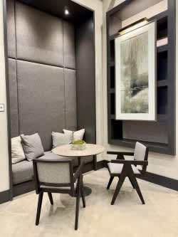 A grey sofa with a white cushion and a grey chair with a wooden frame.