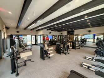 A spacious gym with various exercise equipment and a flat screen TV mounted on the wall.