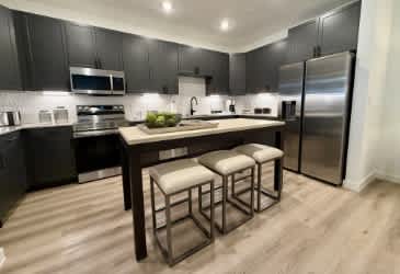 A modern kitchen with a wooden table and bar stools.