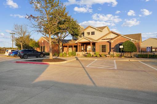 A parking lot in front of a building with a car parked in the lot.
