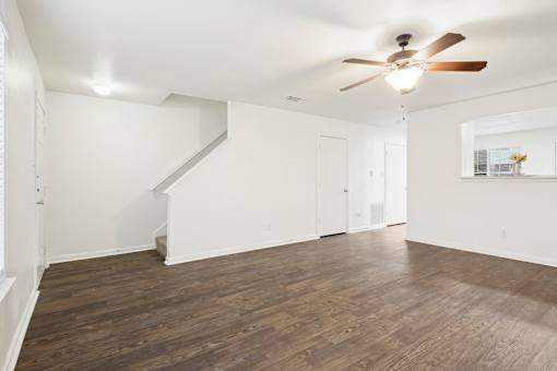 A room with a ceiling fan and wooden flooring.
