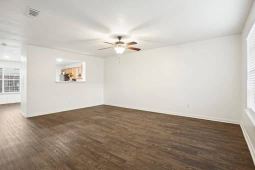 A room with a ceiling fan and wooden flooring.