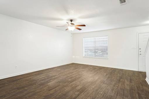 A room with a ceiling fan and wooden flooring.
