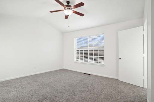 A room with a ceiling fan and a window with blinds.