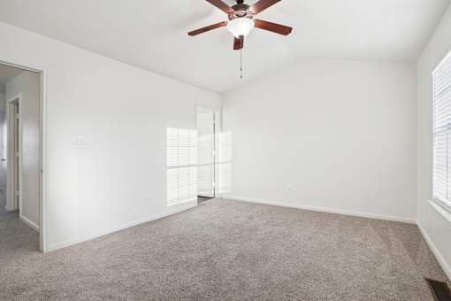 A room with a ceiling fan and carpeted floor.