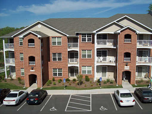 A parking lot in front of a red brick apartment building.