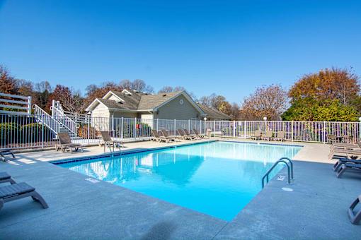 A swimming pool surrounded by a fence and chairs.