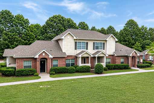 A large house with a black door and windows surrounded by green bushes.