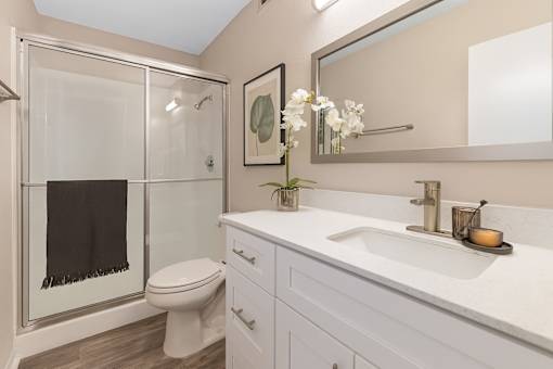A bathroom with a toilet, sink, and mirror.