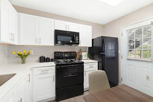 A kitchen with black appliances and white cabinets.