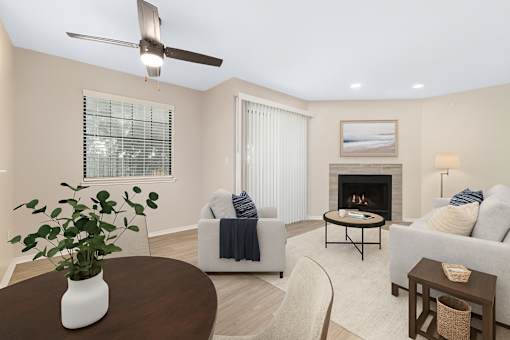 A living room with a fireplace, two couches, a coffee table, and a ceiling fan.