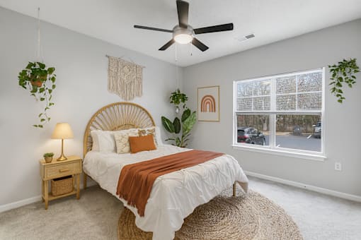 A bedroom with a bed, a ceiling fan, and a window.