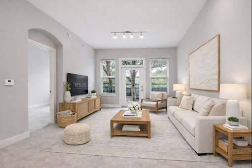 A well-lit, spacious living room with a large couch, a coffee table, and a television.