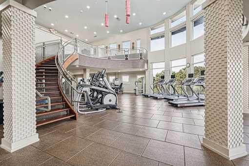 A gym with treadmills, elliptical machines and a staircase.