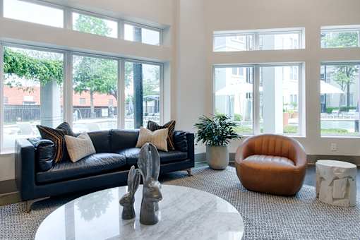 A living room with a black couch and a round orange chair.