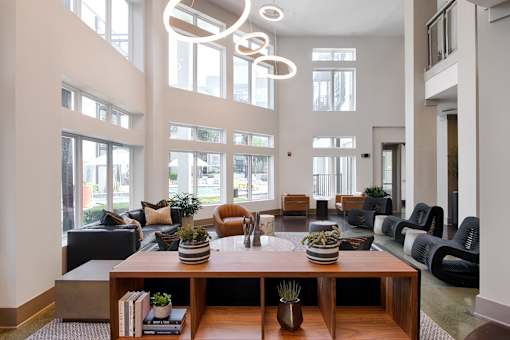 A modern living room with a large wooden coffee table and black and white furniture.