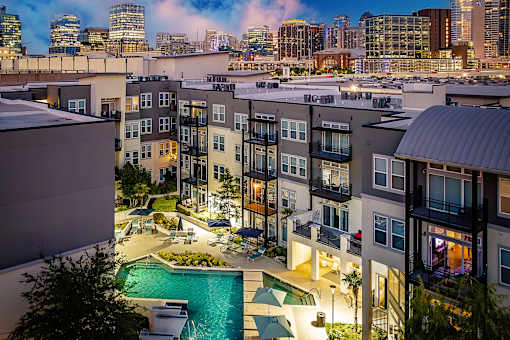 A view of a pool and apartment complex at dusk.