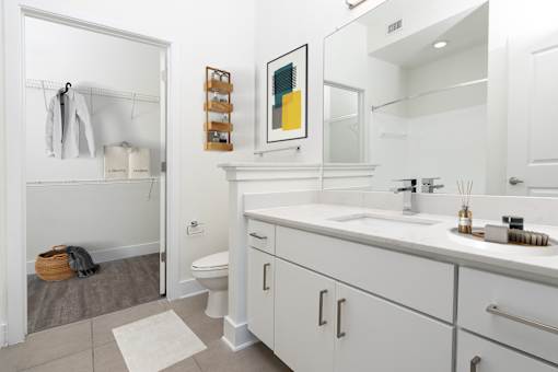 A bathroom with a white toilet, sink, and cabinets.