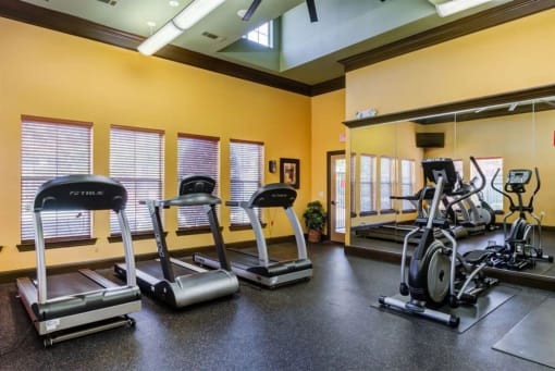 a gym with cardio equipment and weights on the floor