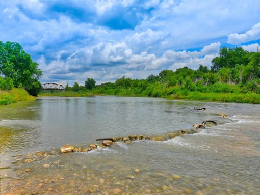 a river with rocks in the water under a cloudy sky