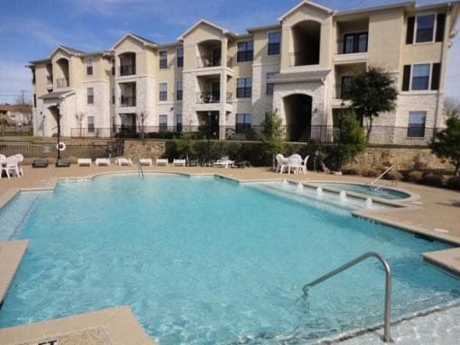 a large swimming pool in front of an apartment building